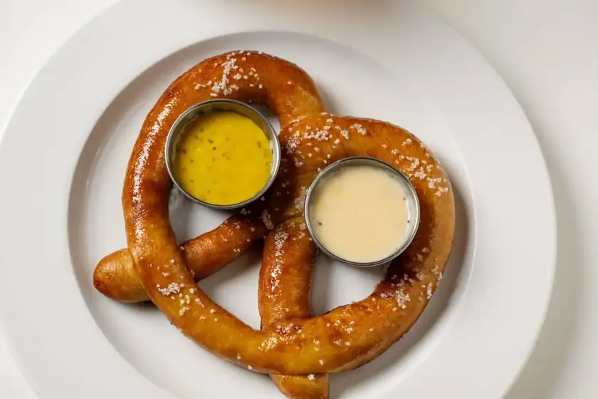 A soft pretzel with mustard and beer cheese dips